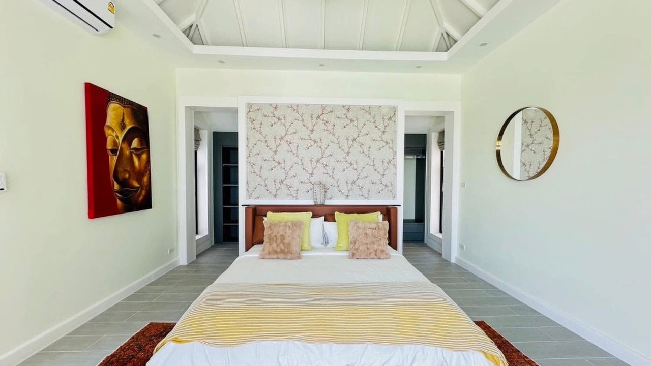 Guest bedroom with gold Buddha artwork and vaulted ceiling