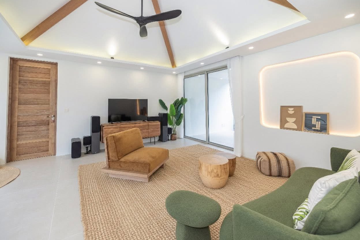Family living room with TV, green sofa and vaulted timber ceiling