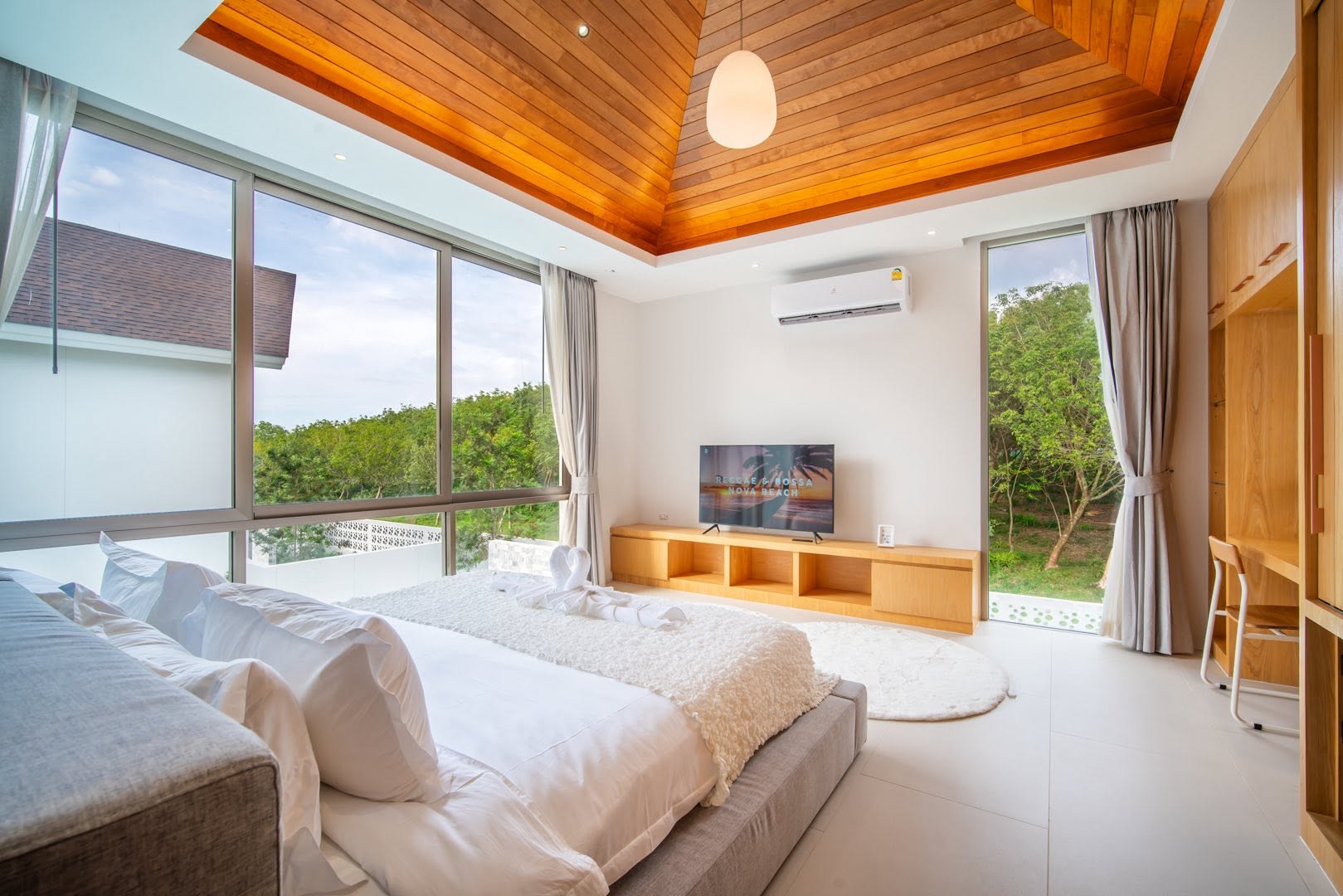 Bedroom with full-height corner windows and treetop views