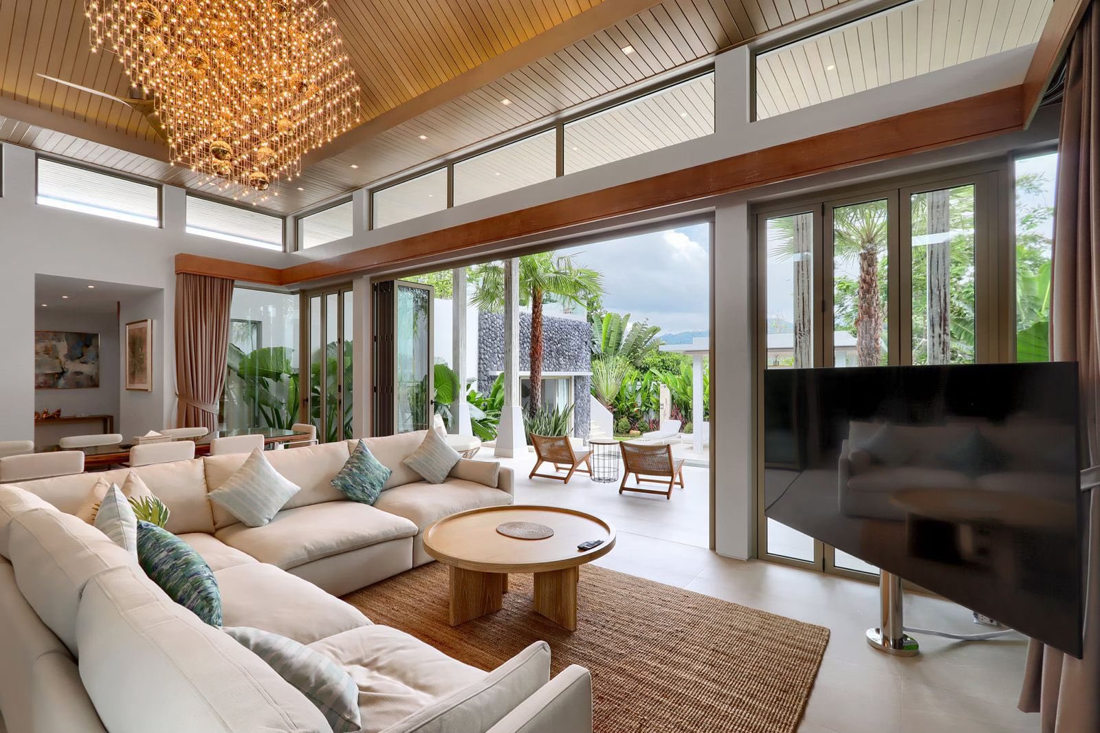 Living room with sectional sofa, designer chandelier and garden views