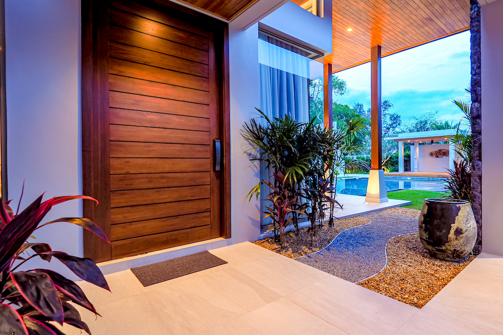 Grand wooden entrance door with tropical landscaping