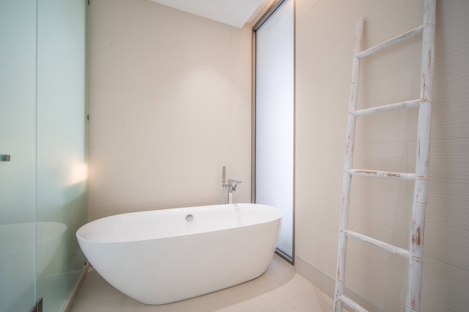 Ensuite with freestanding bathtub beside frosted glass window