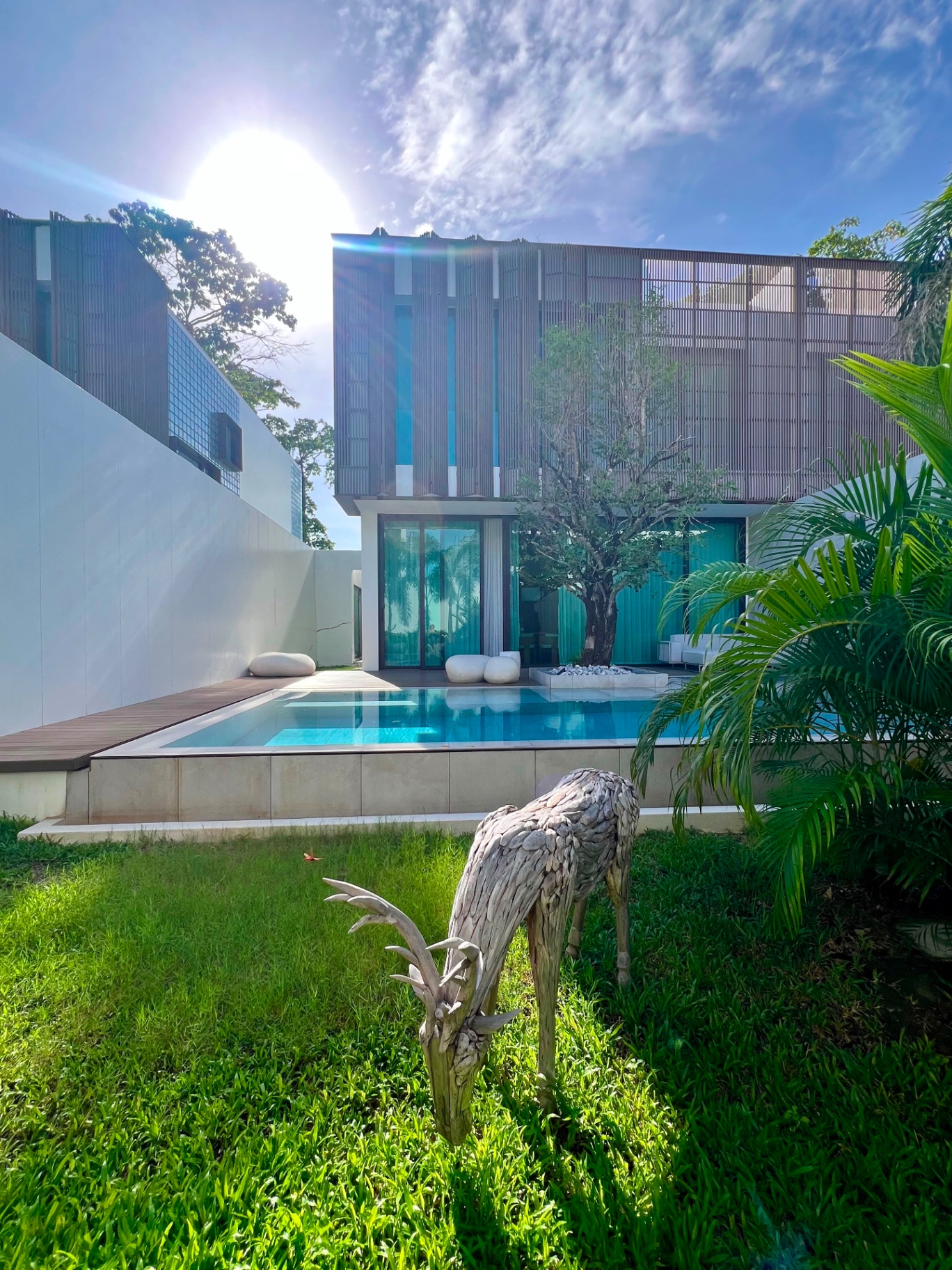 Mono Oxygen pool villa facade seen across the garden lawn