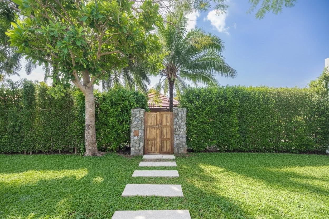 Timber garden gate entrance framed by mature tropical planting