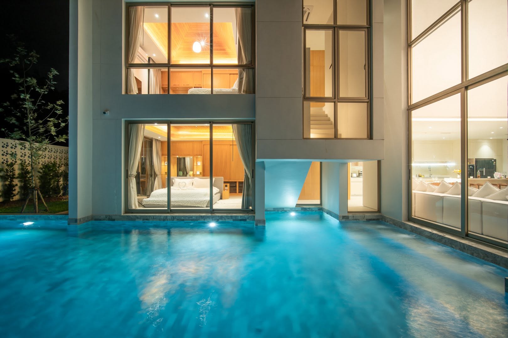 Private pool at night beneath the double-height glass facade