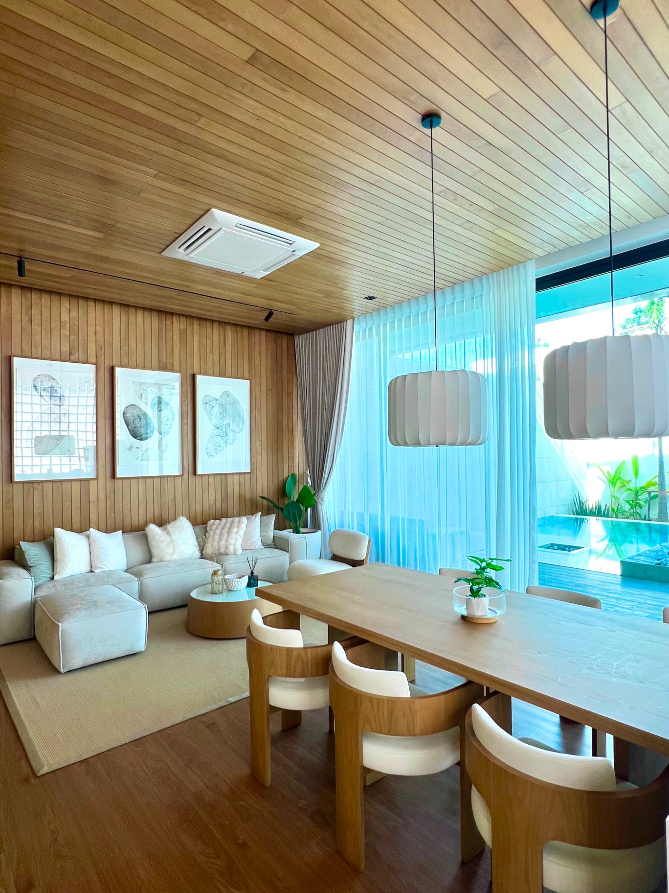 Open-plan living and dining room with timber ceiling and pool view