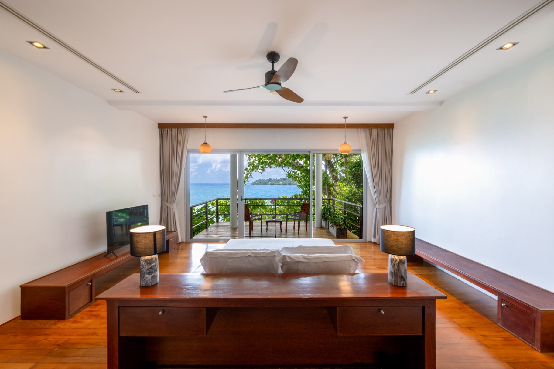 Ocean-view bedroom with twin bedside lamps and balcony