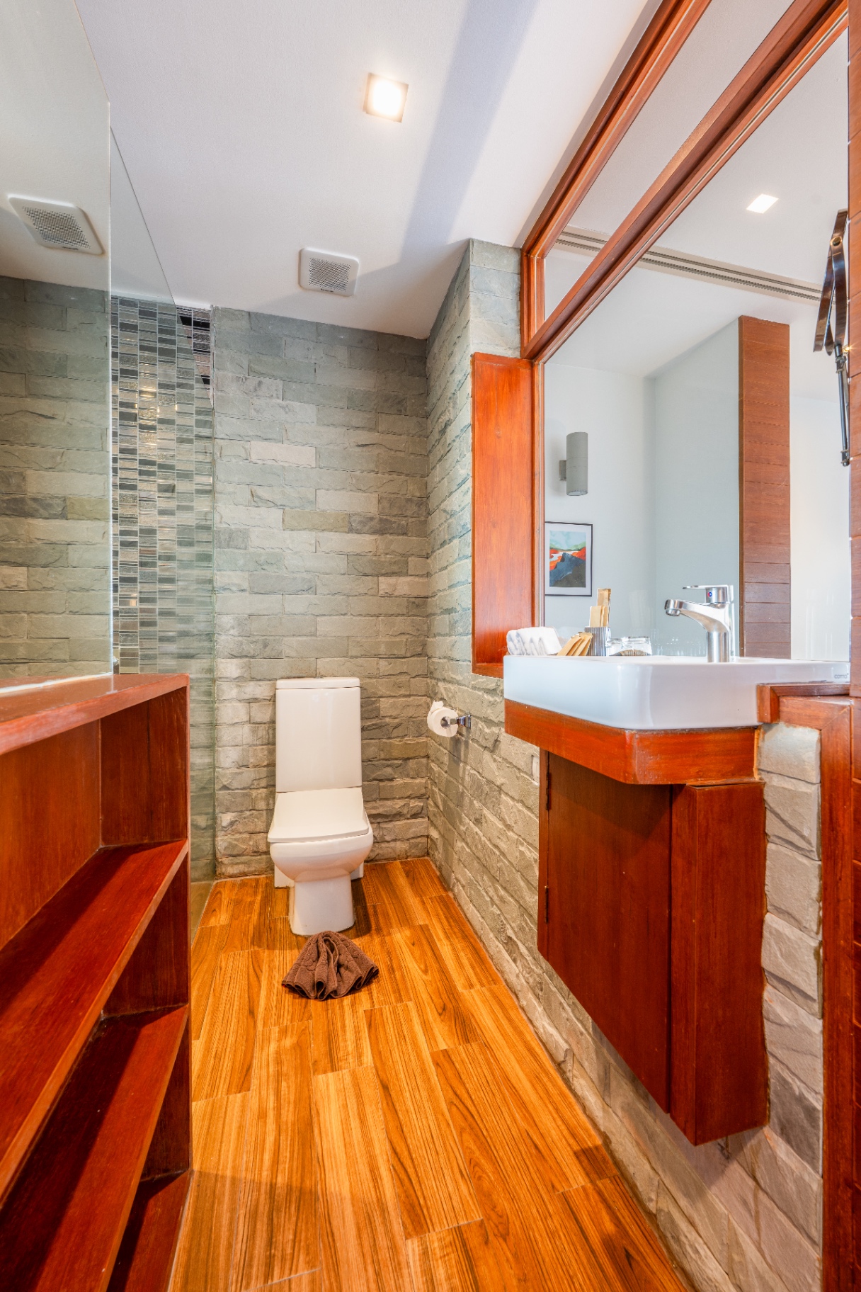 Ensuite bathroom with natural stone walls and teak vanity