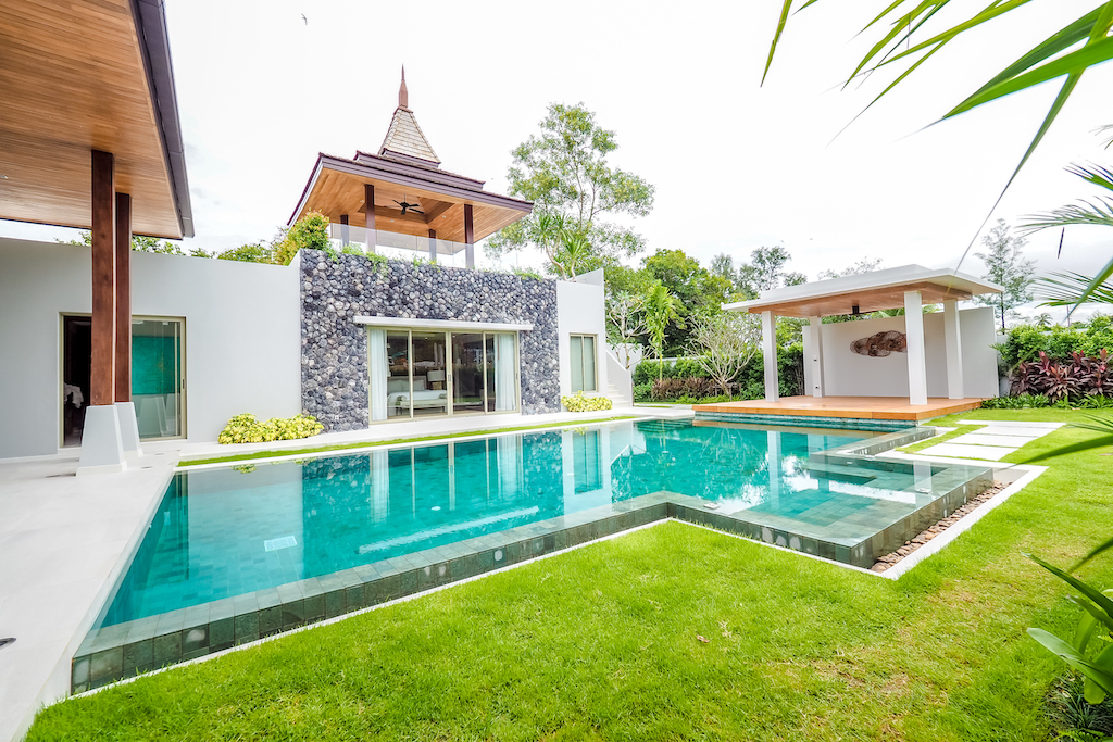 Villa exterior with infinity pool, stone wall and poolside sala
