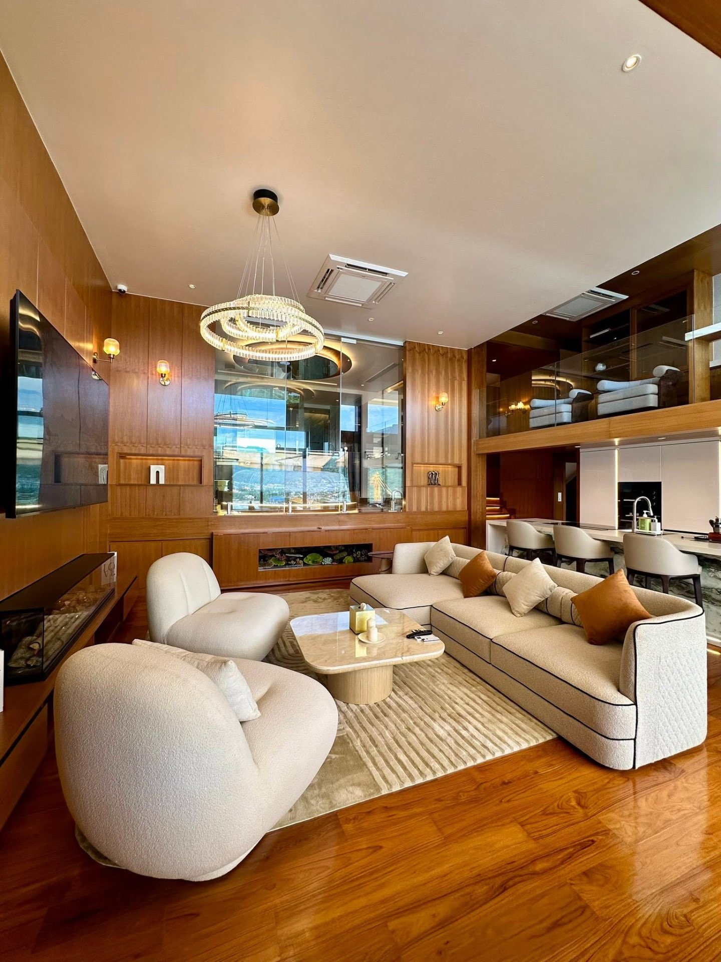 Living lounge with designer chandelier, bouclé seating and sea-view kitchen beyond