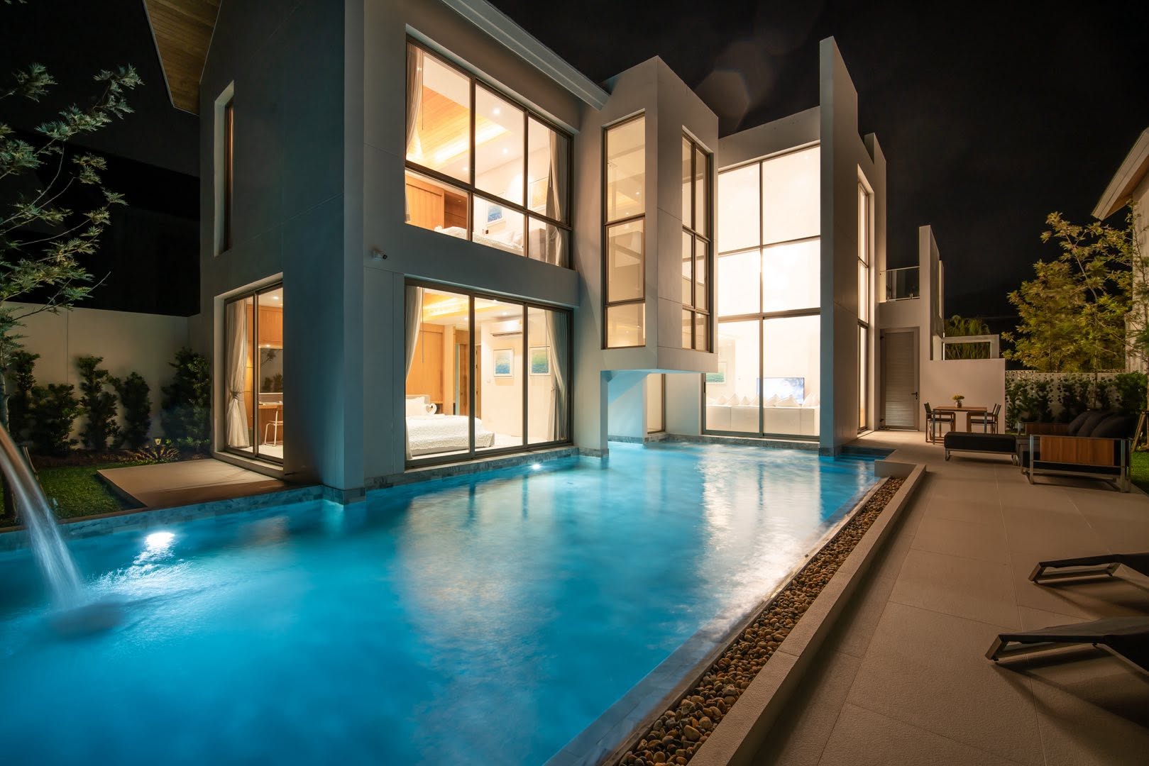 Pool with water feature lit up at night beside the terrace