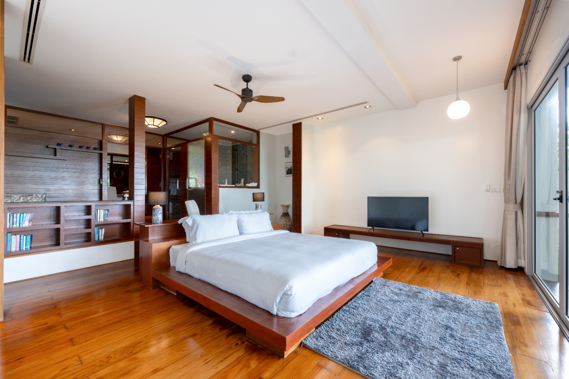 Master bedroom with raised teak platform bed and bookshelf
