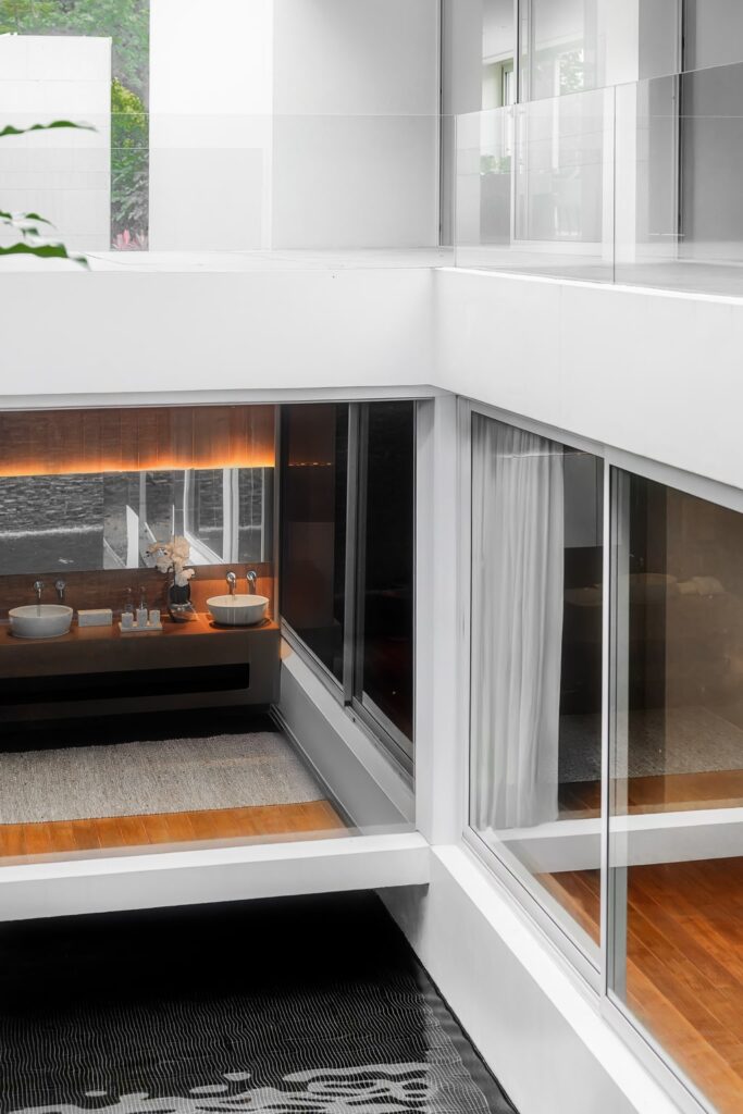 Glass-walled bathroom with double vanity and teak flooring