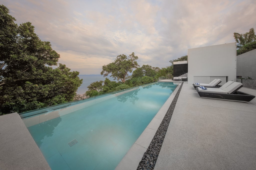 Infinity pool with loungers and ocean views at sunset