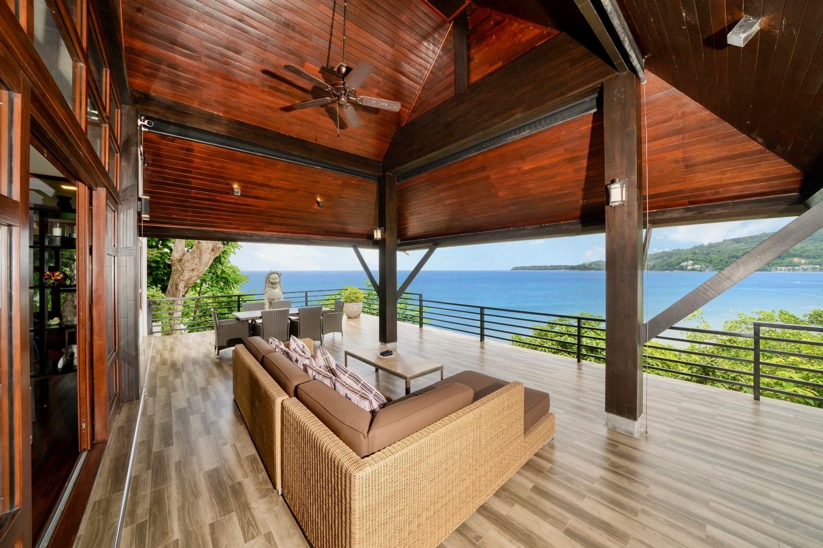 Covered outdoor lounge with rattan sofa and bay views