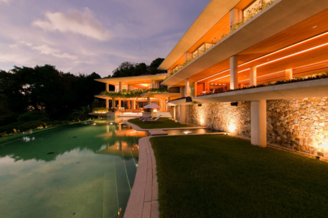 Estate exterior with pool and stone walls at twilight