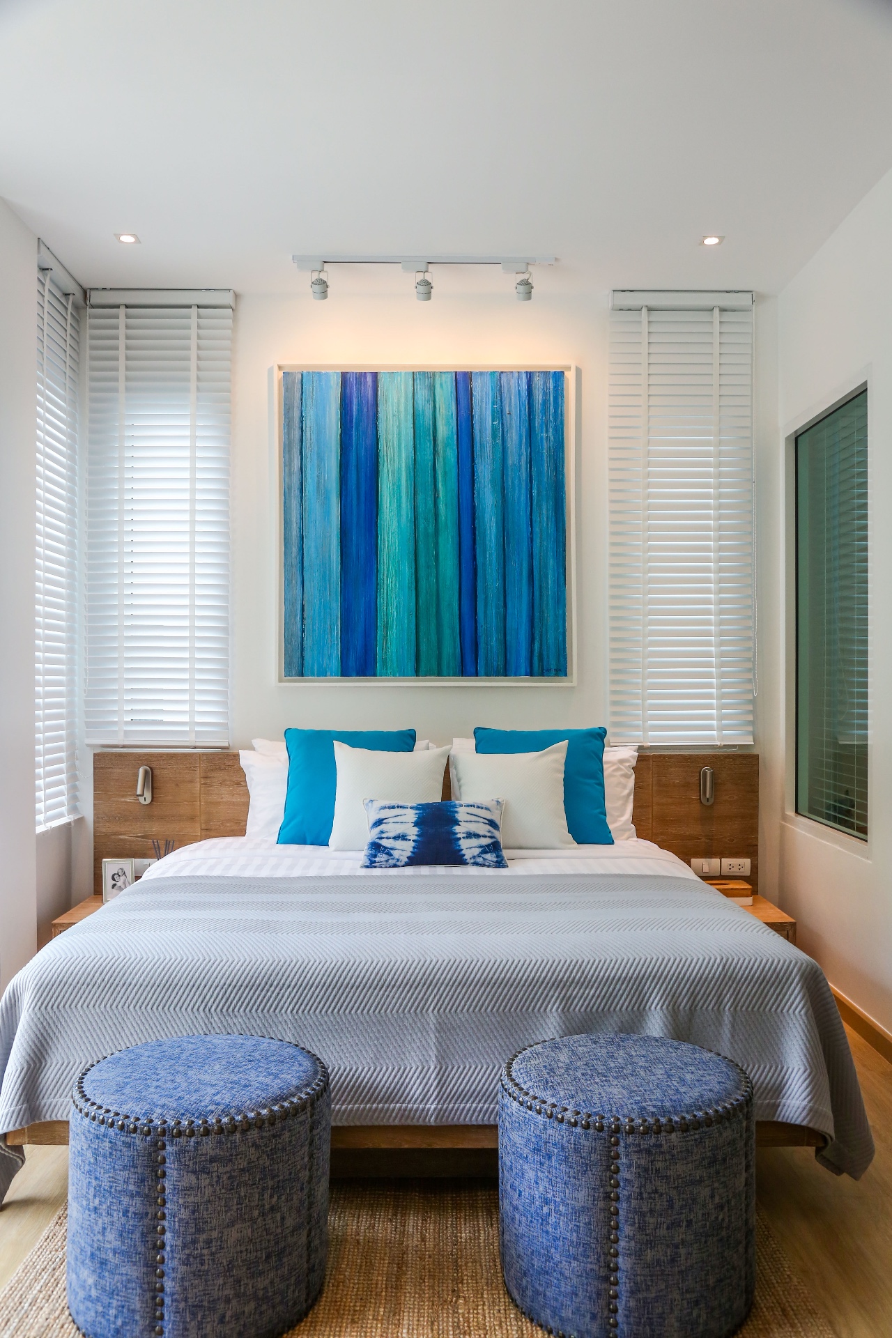 Master bedroom with blue abstract art and teal pillows