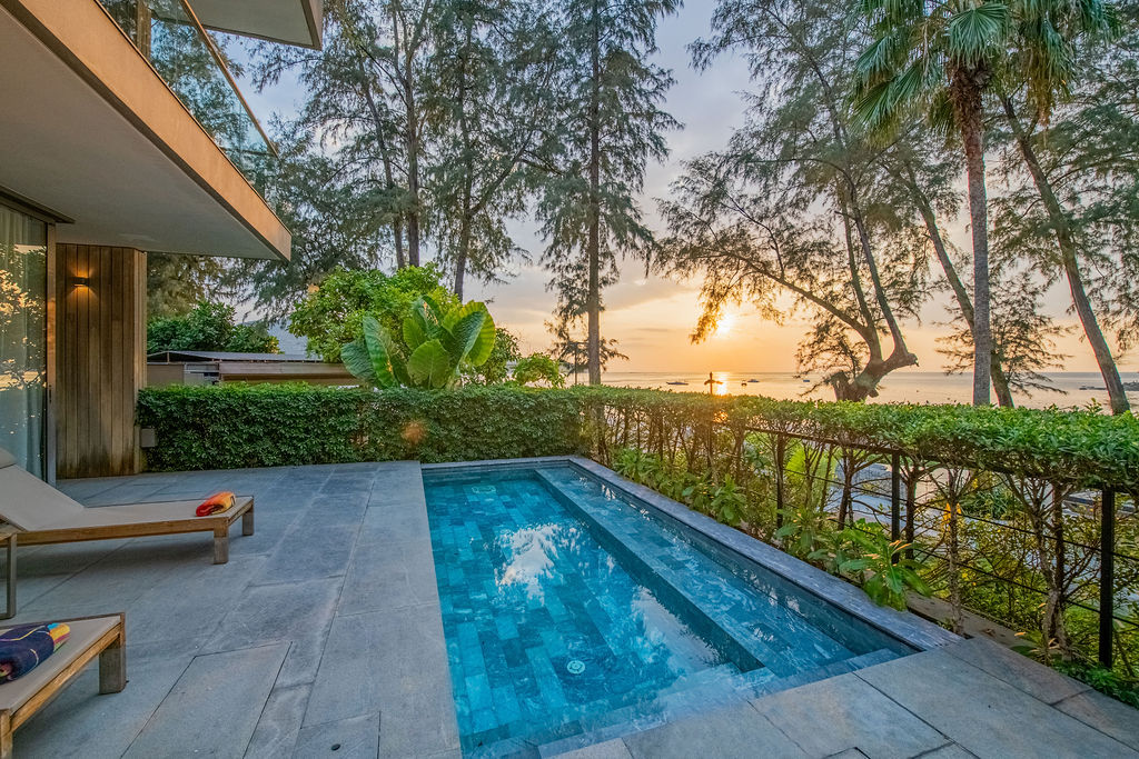 Private pool with ocean sunset views through palm trees